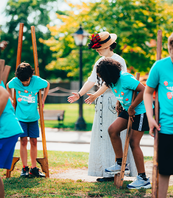 Students in blue shirts playing on wooden stilts